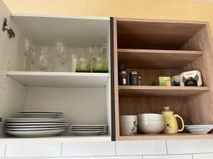a cupboard with plates and bowls and other kitchen items at Ferienwohnung Tina in Burgkunstadt
