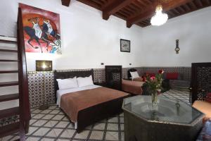 ein Schlafzimmer mit einem Bett, einem Sofa und einem Tisch in der Unterkunft Riad Dwiriyat My Teib in Marrakesch