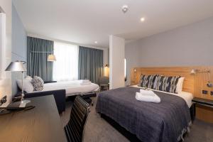 a hotel room with two beds and a desk at Apex City of Edinburgh Hotel in Edinburgh