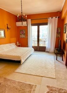 a bedroom with orange walls and a bed and a television at NUX Luxury Apartments in Alexandroupoli