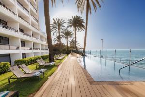 a swimming pool with chairs and palm trees next to a building at Don Gregory by Dunas - Adults Only in San Agustin