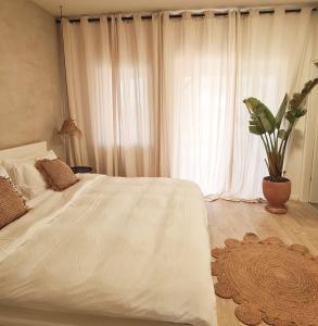 een slaapkamer met een wit bed en een potplant bij cala sun villa קאלה סאן וילה in Kefar HaRif