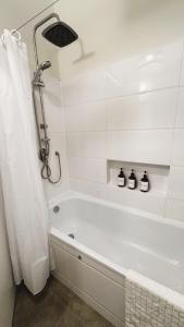 een witte badkamer met een bad en een douche bij cala sun villa קאלה סאן וילה in Kefar HaRif