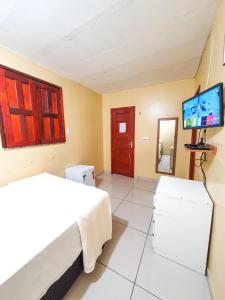 a bedroom with a bed and a flat screen tv at Babylon Village in Algodoal