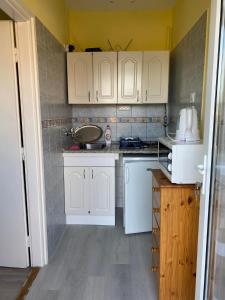 eine Küche mit weißen Schränken und weißen Geräten in der Unterkunft Aranypatak Apartmanház Hévíz in Hévíz