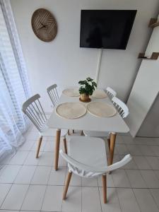 une table et des chaises blanches avec une plante en pot dans l'établissement Magnifique T2 - Le Lagon bleu, au Grau-du-Roi