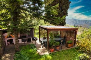 patio trasero con cenador con mesa y chimenea en Oasi Verde, en Castiglione Chiavarese