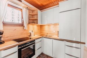 a kitchen with white cabinets and a sink and a stove at Chalet Familie Mertel in Ebene Reichenau in Ebene Reichenau