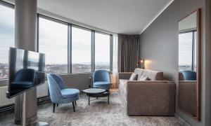 een woonkamer met een bank en stoelen en een tv bij Thon Partner Stavanger Forum Hotel in Stavanger