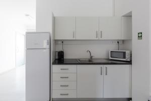 eine weiße Küche mit einer Spüle und einem Kühlschrank in der Unterkunft Smile4Porto Guest House in Porto