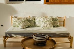 een bed met groene en witte kussens en een mand bij Stilish - Homely House #5 in Sant Ferran de Ses Roques