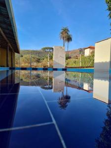 a swimming pool with a view of a palm tree at Sítio Paraíso Serrano em Igarapé in Igarapé