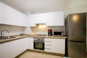 a kitchen with white cabinets and a stainless steel refrigerator at 422 Quiet, beautiful flat with sea view in Playa Paraiso