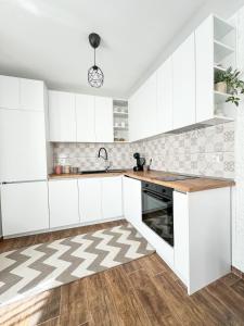 a white kitchen with white cabinets and a sink at Апартамент за гости Лена Златоград in Zlatograd