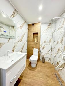 La salle de bains est pourvue d'un lavabo blanc et de toilettes. dans l'établissement Апартамент за гости Лена Златоград, à Zlatograd