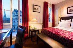 パリにあるホテル デュケヌ エッフェルのベッド、デスク、窓が備わるホテルルームです。