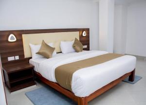 una camera con un grande letto con testiera in legno di The Grand Rocks Hotel Limited a Eldoret