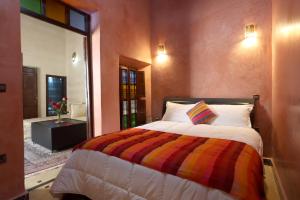 um quarto com uma cama grande e um cobertor colorido em Riad Dwiriyat My Teib em Marrakech
