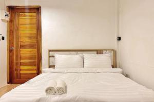 a bedroom with a bed with two white slippers on it at Chubby 5 Room 4 in Ban Bang Bamru