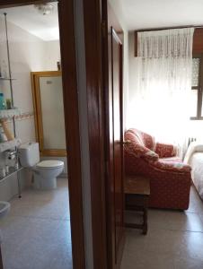 a bathroom with a toilet and a couch and a window at Cuarto Privado Doble en Toledo in Toledo