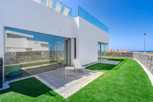 una silla blanca sentada en un césped frente a una casa en Villa Estándar 1 - Casangular by Upper, en Adeje