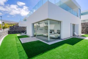 una casa blanca con un patio con césped verde en Villa Estándar 1 - Casangular by Upper, en Adeje