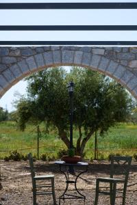 a table with a lamp and two chairs in front of a tree at La Familia Luxury Private Maisonettes near the sea in Gythio