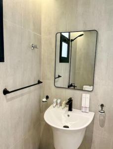 ein Badezimmer mit einem weißen Waschbecken und einem Spiegel in der Unterkunft Spacious new 2 bedroom Apt-in amazing location B33 in Riad