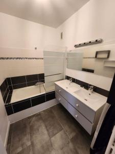 - une salle de bains blanche avec deux lavabos et un miroir dans l'établissement L'escapade Familial seh'loué, à Saint-Brieuc
