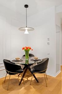 a dining room table with chairs and a vase of flowers at ONE Luxury Apartments in Bucharest