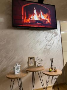 two tables with a tv on a wall with a fireplace at Apartman Nađa in Bileća