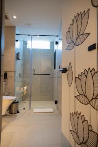 a bathroom with a shower and a glass door with flowers on the wall at Zibe Luxe Kakinada by GRT Hotels in Kākināda +48 photos