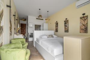 a bedroom with a bed and two green chairs at Jardin Chic in Fort-de-France