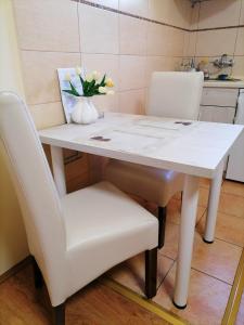 a white table with two chairs and a vase of flowers at Apartman Biljana in Šabac