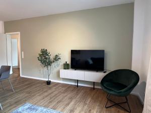 uma sala de estar com uma televisão e uma cadeira em Business Apartment Kranich: 3 Zimmer, Top Infrastrukturlage HH Langenhorn, Nähe Airport em Hamburgo