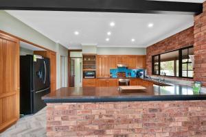 a kitchen with a black refrigerator and a brick wall at 5br Bbq Hot Tub Family Farm Stay Homestead in Lovedale