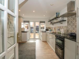 a large kitchen with white cabinets and appliances at The Stables in Wisbech