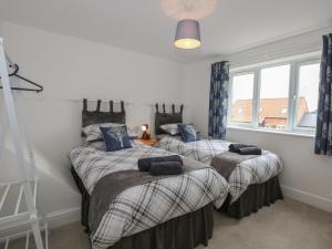 two twin beds in a room with two windows at The Stables in Wisbech