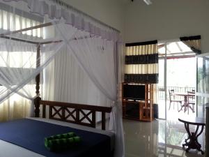 a bedroom with a bed with a canopy and a television at Coral Palm Villa and Apartment in Unawatuna