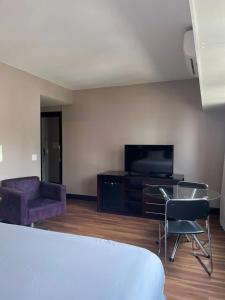 a bedroom with a tv and a couch and a chair at Getaflat-1504 Berrini 4 estrelas in São Paulo