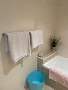 La salle de bains est pourvue d'une baignoire, de serviettes et d'un seau bleu. dans l'établissement Amazing water view class large holiday home, à Gold Coast