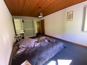 ein großes Bett in einem Zimmer mit Holzdecke in der Unterkunft le Relais du Doubs in Soubey
