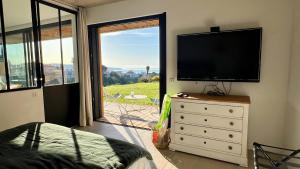 una camera da letto con TV a schermo piatto su un comò di La Coulina a Nizza