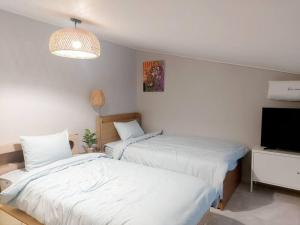 two beds in a room with a tv and a room withermottermott at Jin House Incheon Geomamstation in Incheon