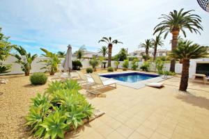 un patio trasero con piscina y palmeras en Golondrina - panoramic hillside holiday house in Moraira, en Moraira