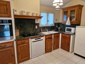 una cocina con armarios de madera y electrodomésticos blancos en Maison le murier, en Aubignan 4 fotos más