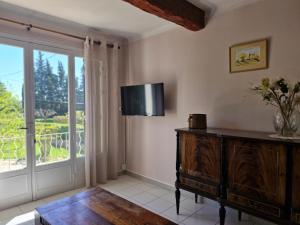 Una sala de estar con televisión y una gran ventana. en Maison le murier, en Aubignan