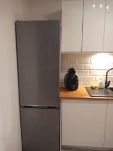 a stainless steel refrigerator in a kitchen with white cabinets at Apartament w Starym Mlynie Loft Różanka in Wrocław +23 photos
