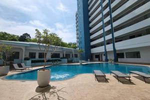 a pool with chairs and a potted tree next to a building at Mutiara Melaka Beach Resort-Rumah Bonda Ohana in Malacca