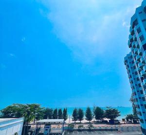 a view of a building and the ocean with palm trees at Mutiara Melaka Beach Resort-Rumah Bonda Ohana in Malacca
